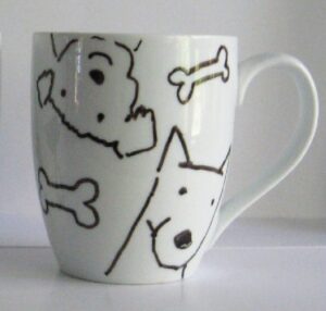 A white mug with black dogs and bone designs on it.