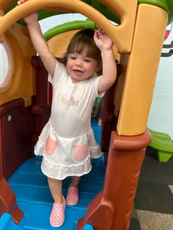 A little girl standing on top of a play structure.