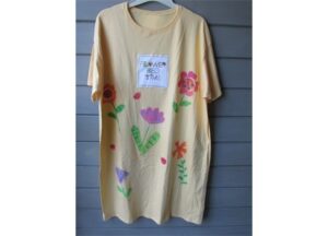 A yellow t-shirt with flowers painted on it.