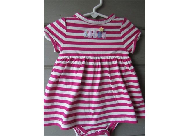 A pink and white Striped Personalized Dress with Rompers hanging on a hanger.