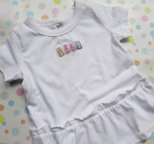A white shirt with the word baby spelled out in letters.