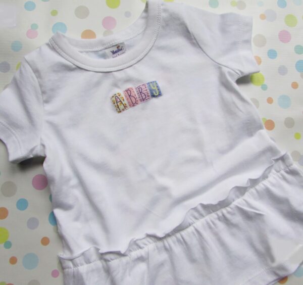 A white shirt with the word baby spelled out in letters.