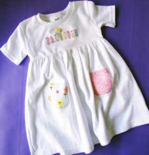 A white dress with patches on the front pocket.