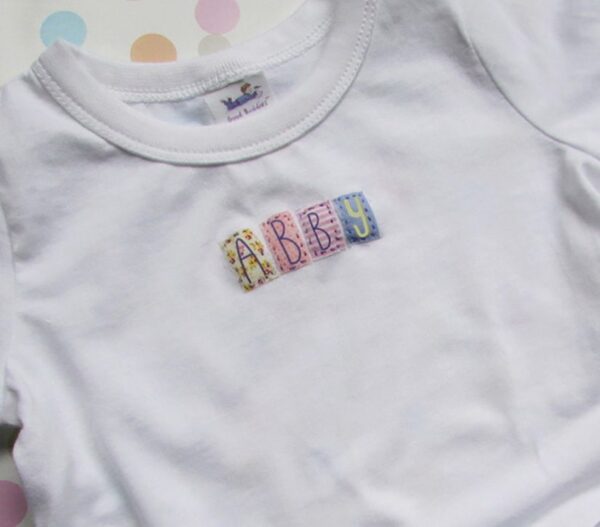 A white shirt with the name abbey spelled out in fabric.