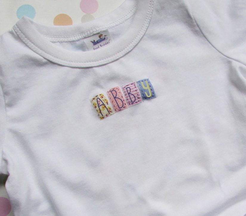 A white Baby Onesie or T-Shirt - Personalized with the word abbey on it.