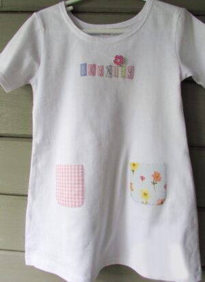 A white t-shirt with patches and flowers on it.